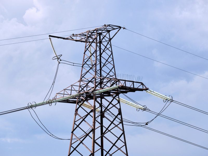 High voltage tower with electric power lines transfening electrical energy through cable wires.